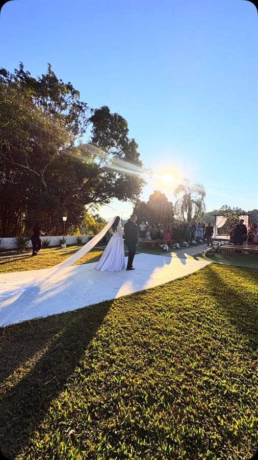 Noivos no altar ao pôr do sol, com o corredor de cerimônia e os convidados