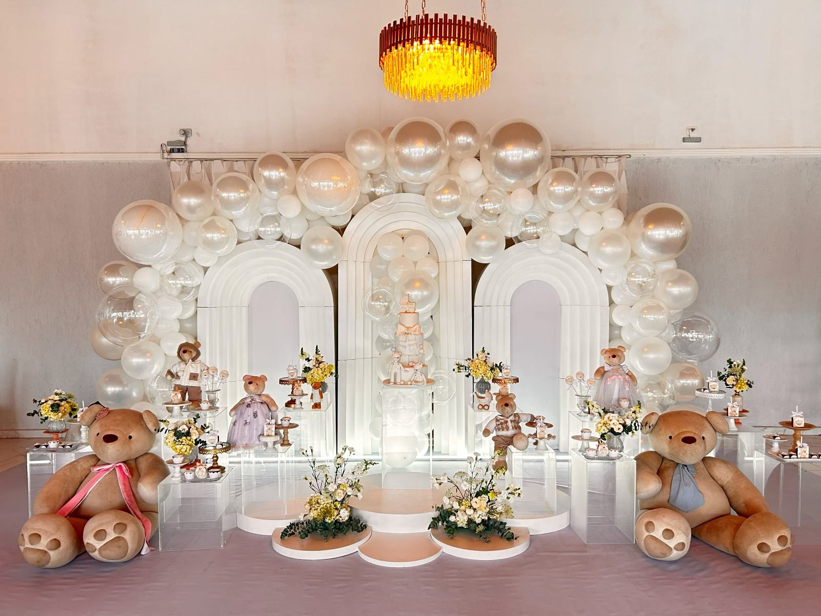 Decoração de chá revelação com arcos, balões dourados e ursinhos de pelúcia